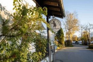 Tante Paula von außen zu sehen, mit Efeu an der Außenwand und Logo als Schild an der Wand, an einem schönen, sonnigen Herbsttag.