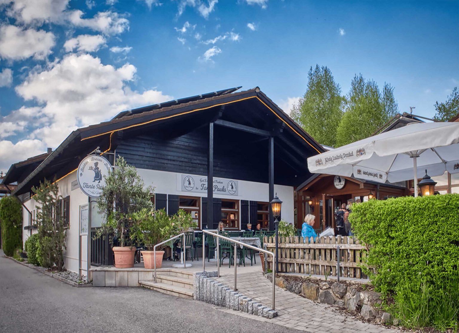 Tante Paula am Hopfensee von außen mit einladendem Biergarten und schönem Wetter mit blauem Himmel.